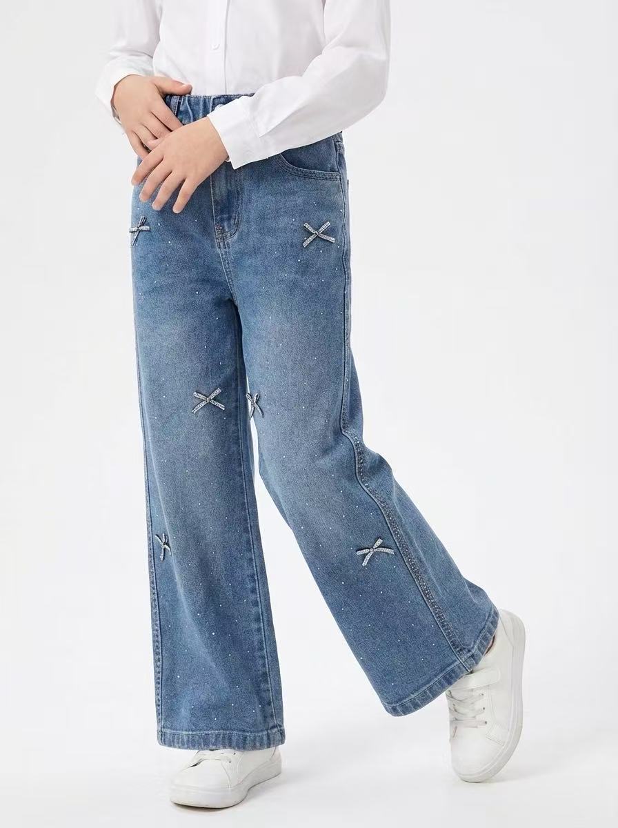 Mayorista Fiona & Co - Vaqueros anchos azules para niña con detalles de strass y lazos Mayorista Fiona & Co - Vaqueros anchos azules para niña con detalles de strass y lazos