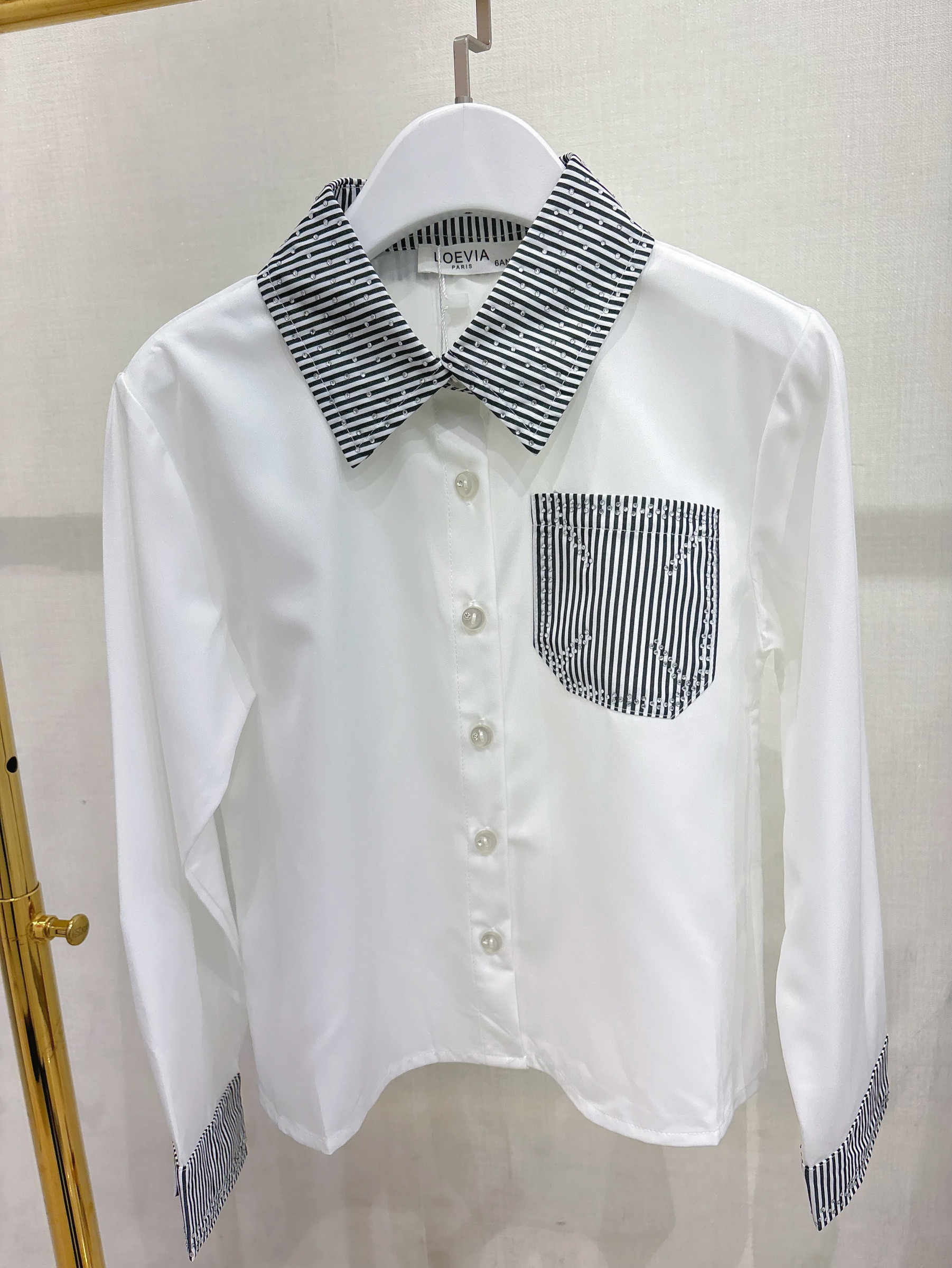 Grossiste LOEVIA - Chemise fillette avec une poche, col et extrémité des manches rayés et strass sur les boutons poche et col