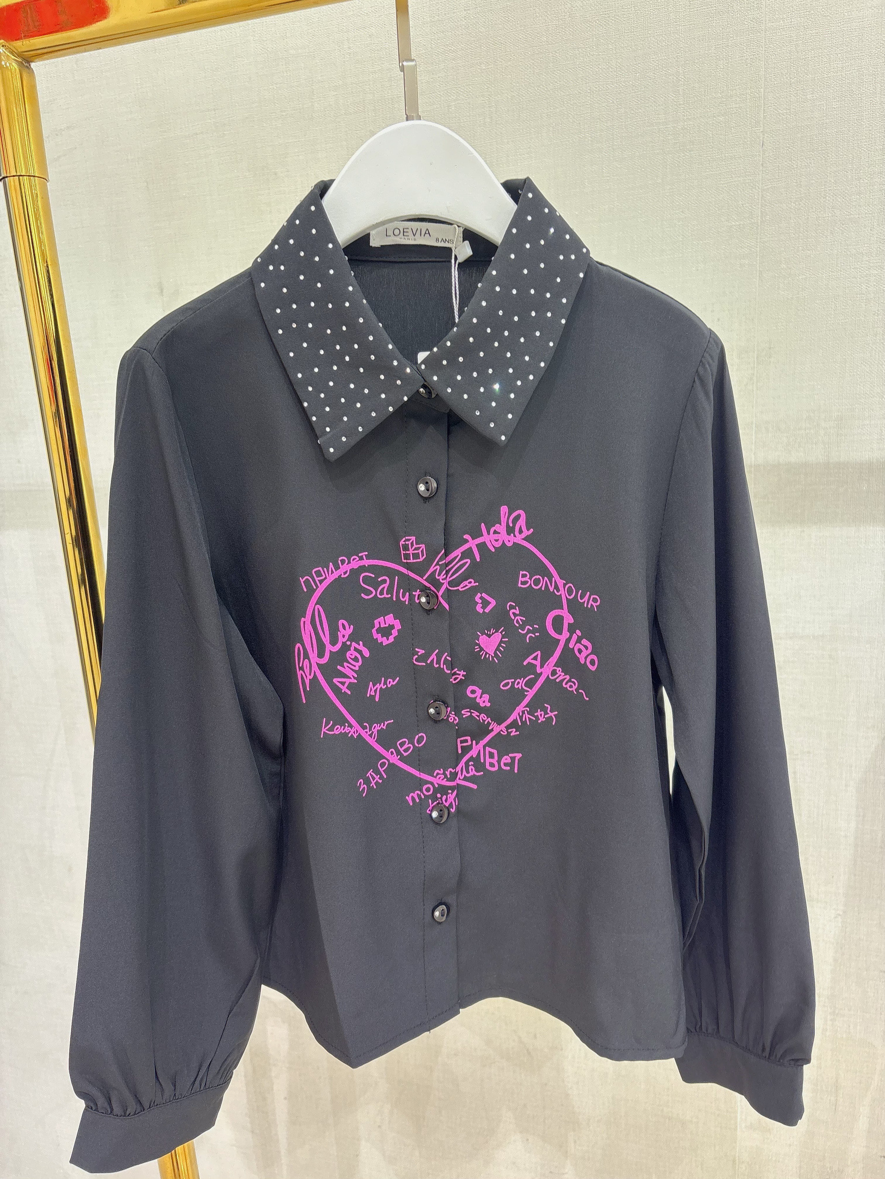 Grossiste LOEVIA - Chemise fillette avec strass au niveau du col et un coeur avec des bonjours de différentes langues