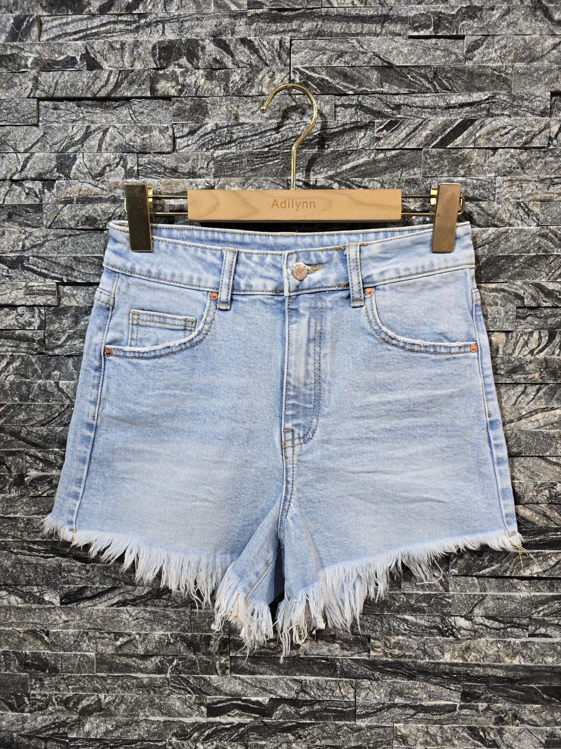 Grossiste Adilynn - Short en jeans bleu, bas effiloché, cinq poches, fermeture à zip et bouton