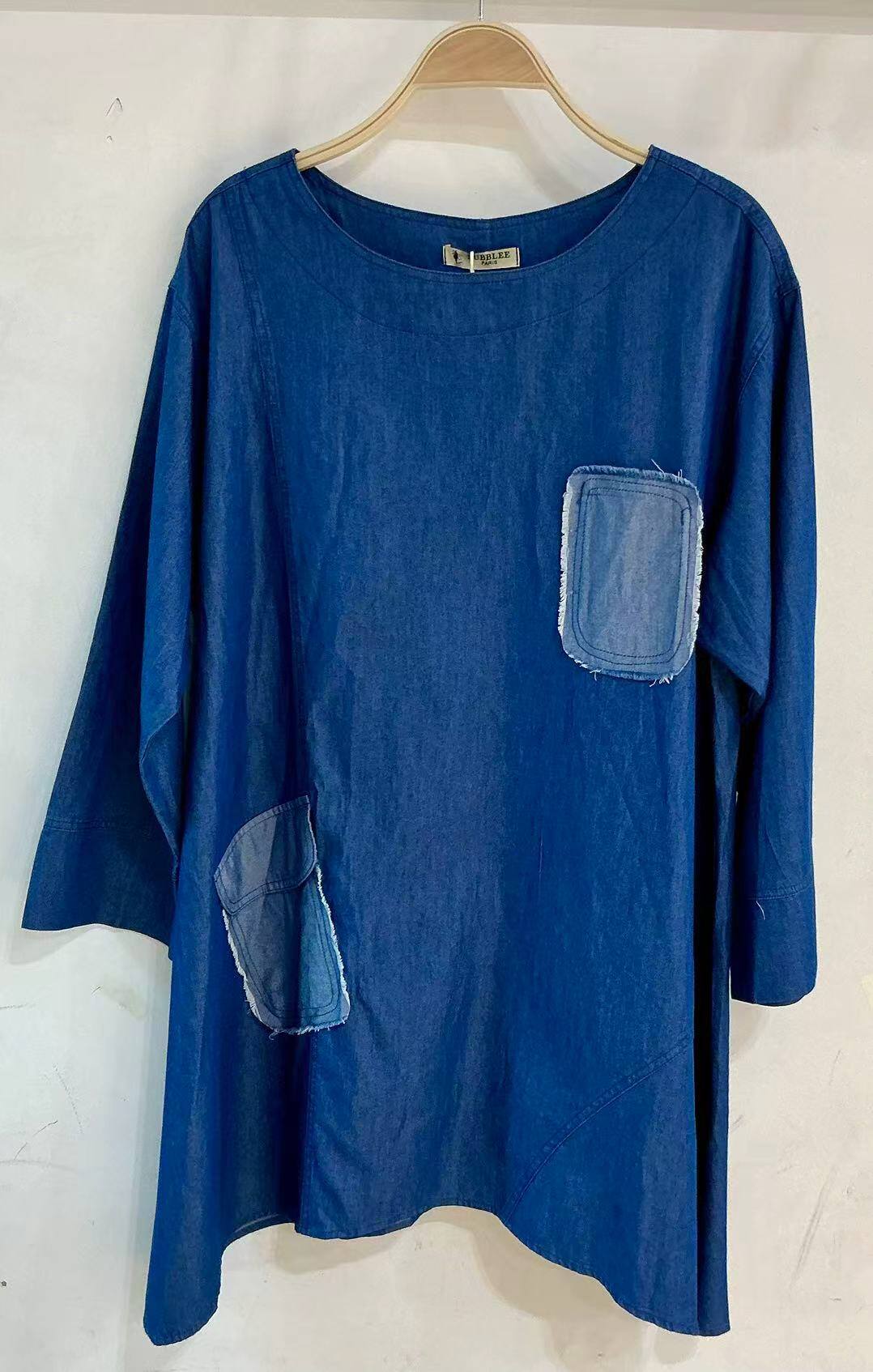 Boat neck blouse with an inverted pocket.