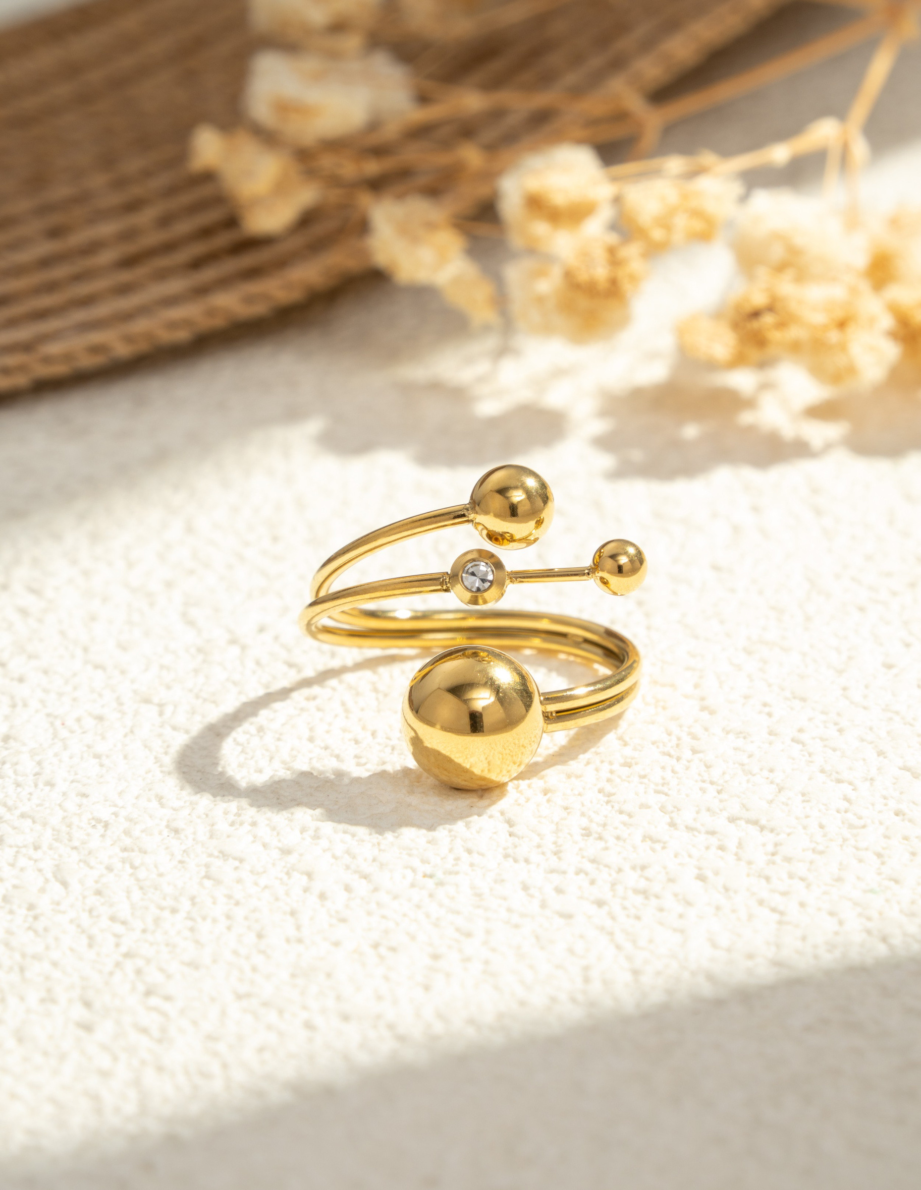 Großhändler COSMOS - Goldener Ring mit drei modernen Kugeln und einem leuchtenden Stein in Edelstahl