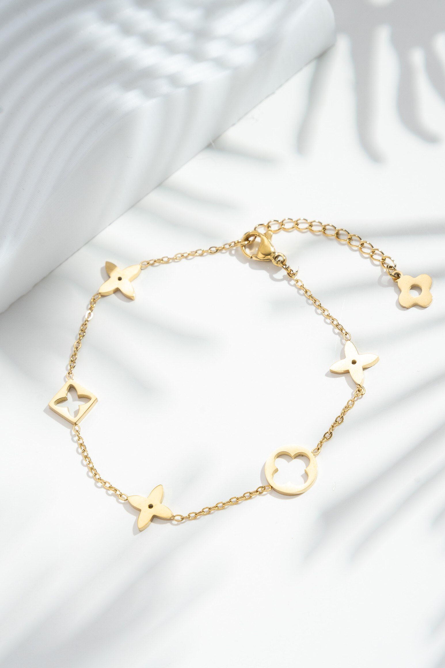 Grossista COSMOS - Bracciale dorato con charms floreali traforati in acciaio inossidabile — delicatezza e poesia