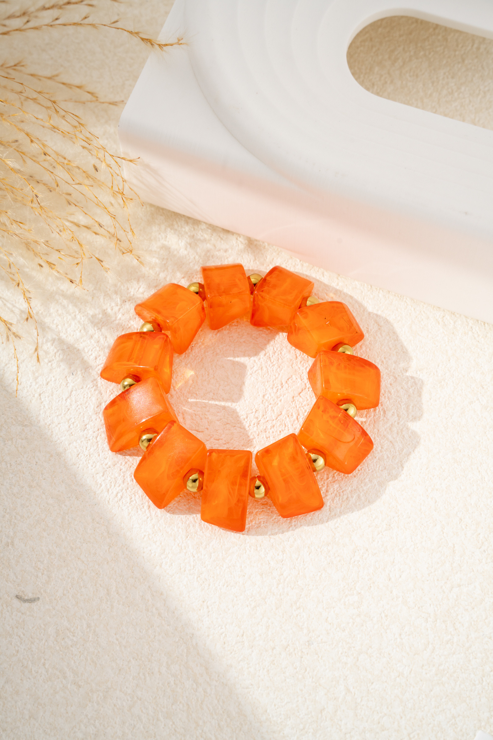Grossiste COSMOS - Bracelet résine orange marbrée acier inoxydable doré perles carrées élastique