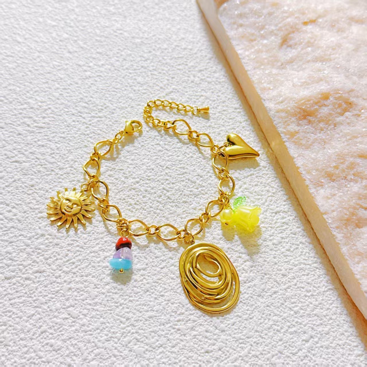 Grossiste COSMOS - Bracelet Doré à Breloques Symboliques et Pendentif Spirale Sculptée