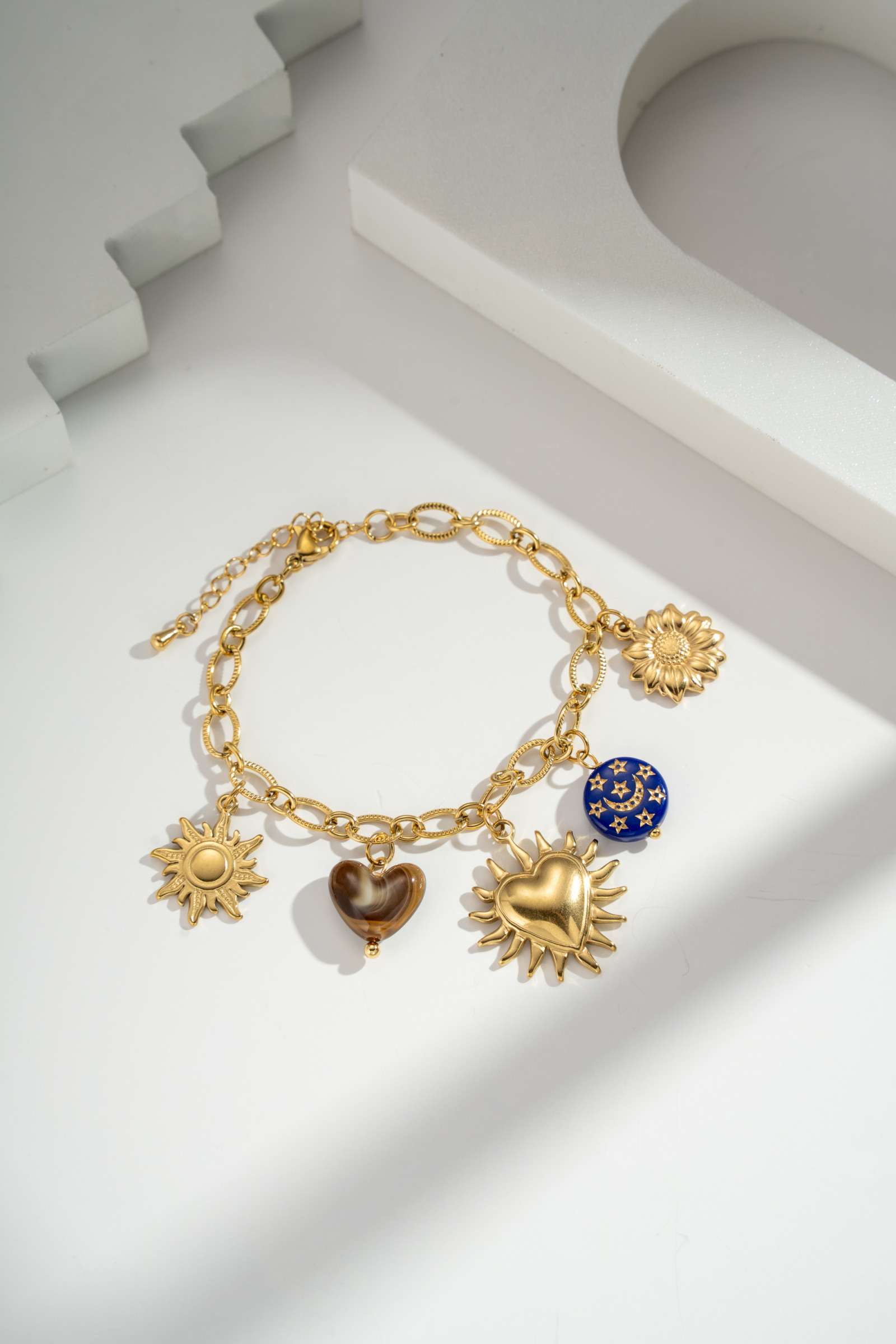 Großhändler COSMOS - Elegantes und schickes verstellbares Armband aus goldfarbenem Edelstahl mit Sonnen-, Mond- und Sternanhängern
