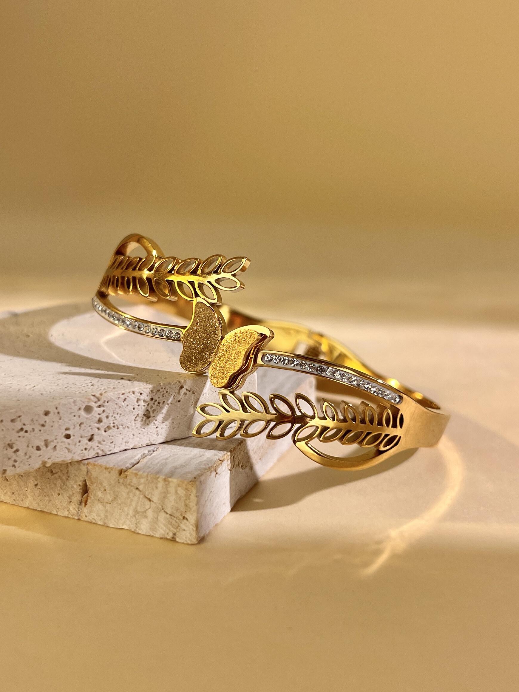 Grossiste COSMOS - Bracelet jonc ajouré motif feuille avec pendentif papillon – acier inoxydable