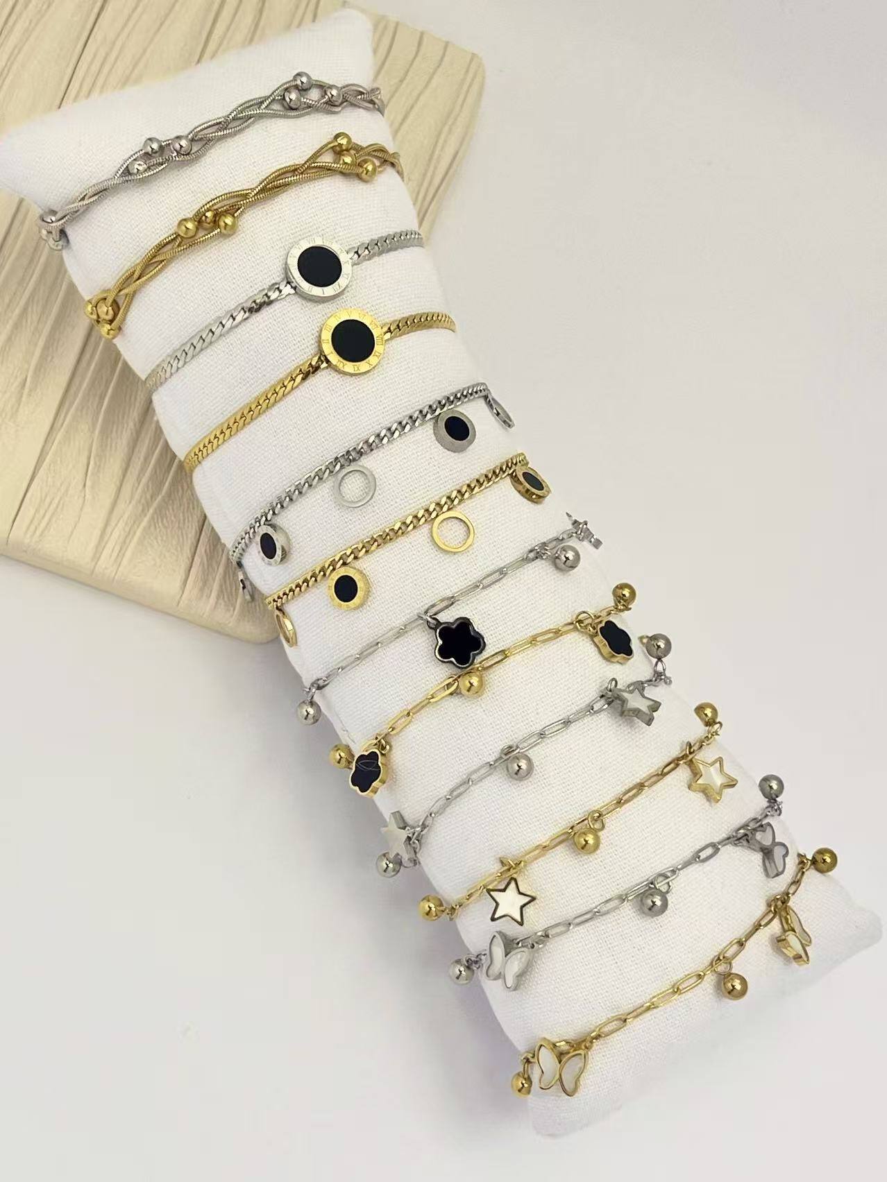 Großhändler COSMOS - Set aus 12 gold- und silberfarbenen Charme-Armbändern aus Edelstahl - Kostenloses Kissen-Display