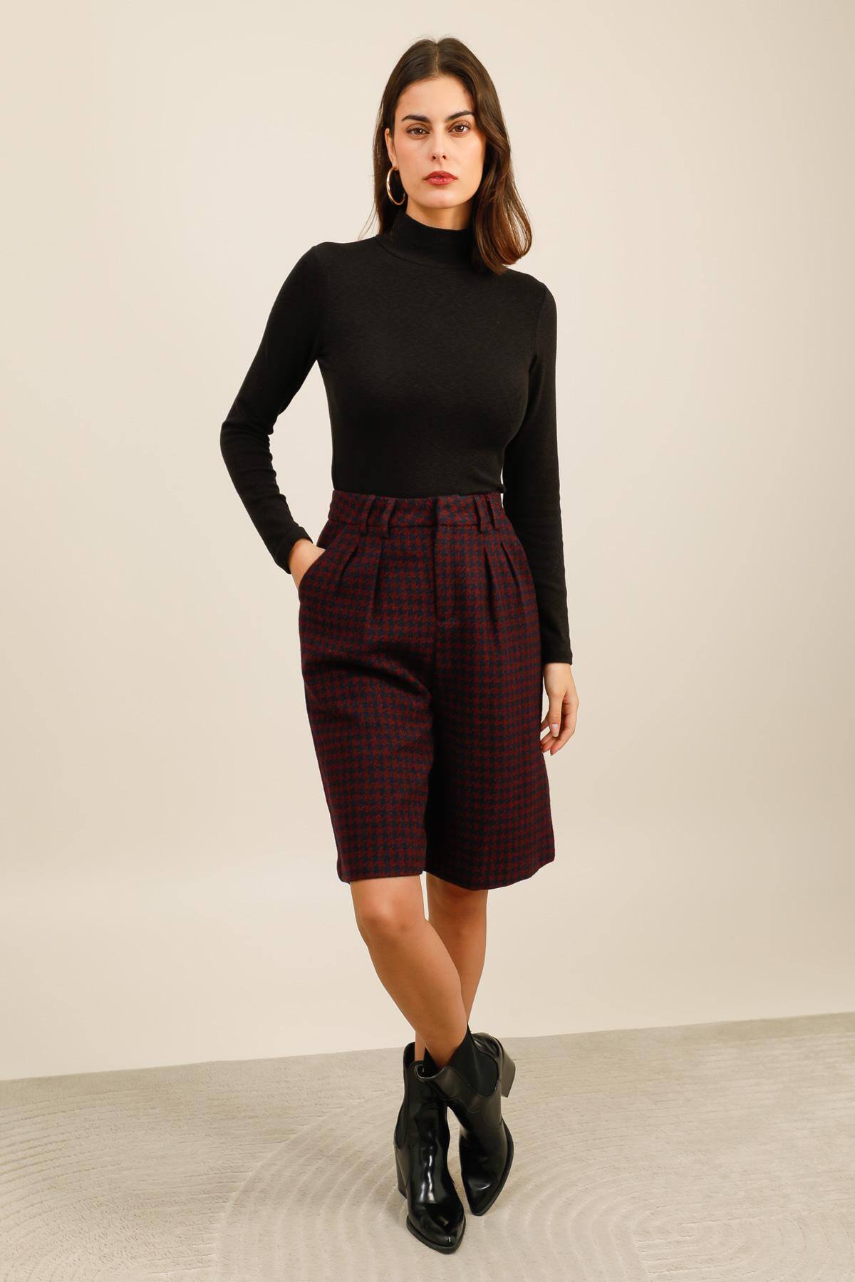 Bermuda à motif pied-de-poule.  Il présente une coupe droite légèrement évasée et une taille haute soulignée par une ceinture à passants.  Des poches plaquées boutonnées à l’arrière ajoutent une touche structurée et élégante.