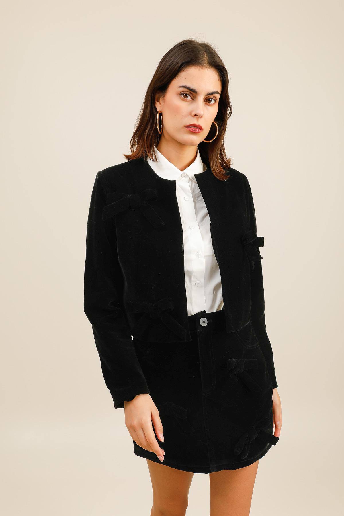 Veste courte en velours au toucher doux.  Elle présente une coupe droite et un col rond épuré. De jolis nœuds en velours ornent le devant de la veste, apportant une touche féminine et délicate à la pièce.