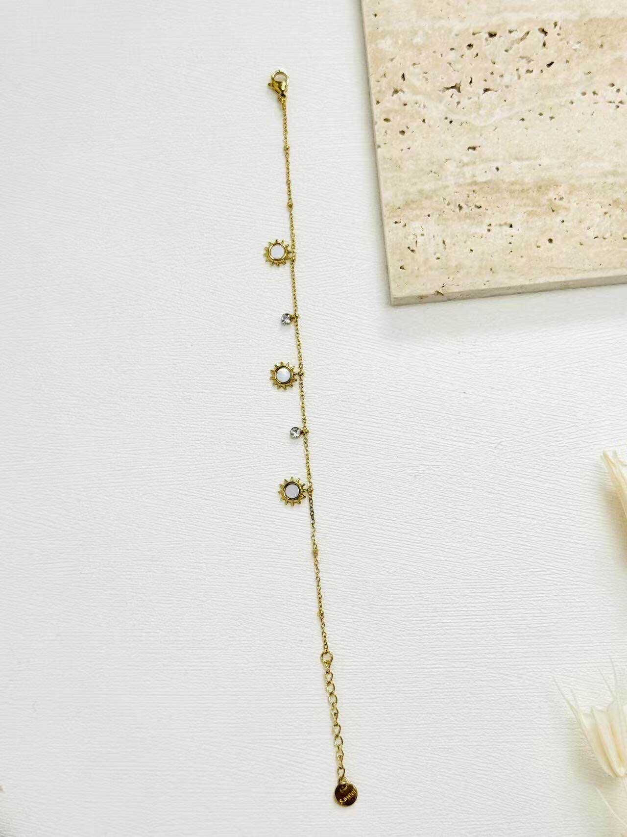 Grossiste Eclador Bijoux - Bracelet en acier Inoxydable avec des pendentifs en forme de soleil nacré.