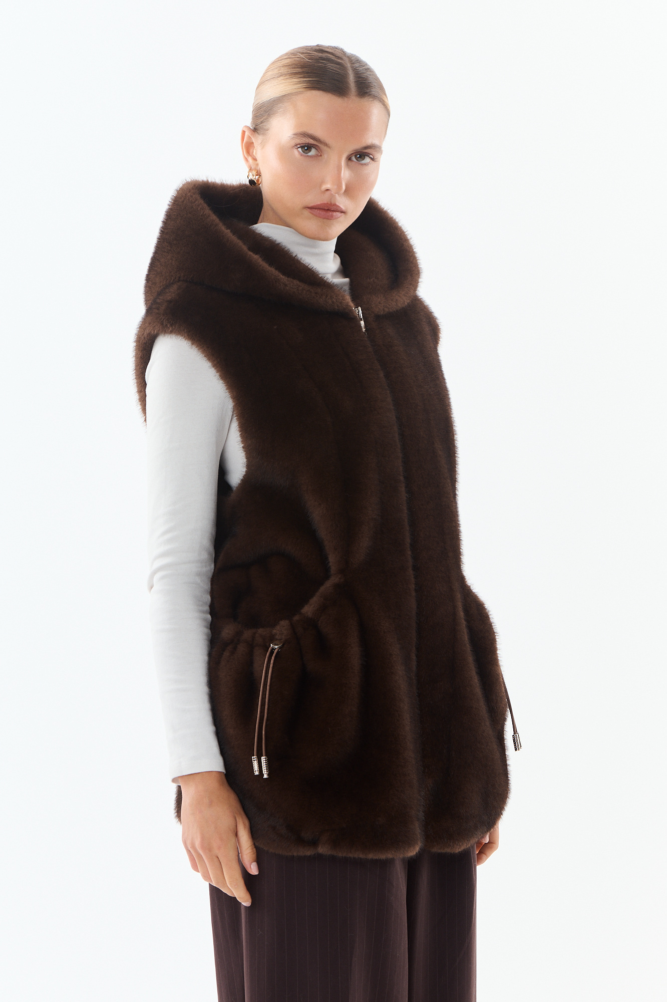Grossista Giovanni Paris - Gilet senza maniche in pelliccia sintetica con cappuccio, taglio oversize, tasche laterali oversize, chiusura con zip, aderente in vita