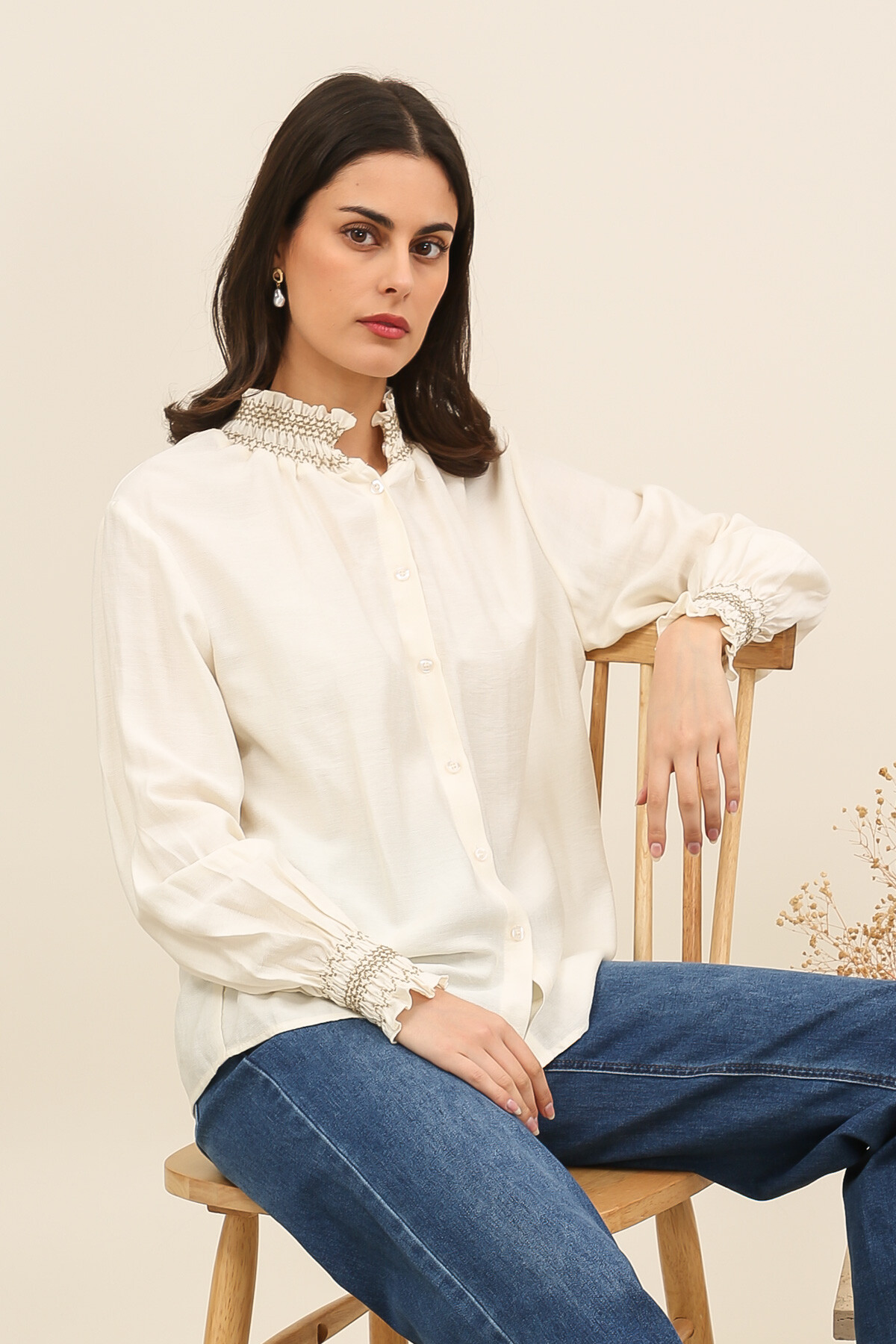 Grossiste Inspiration Studio - Blouse fluide écrue à col smocké et poignets froncés, alliant élégance intemporelle et féminité raffinée.