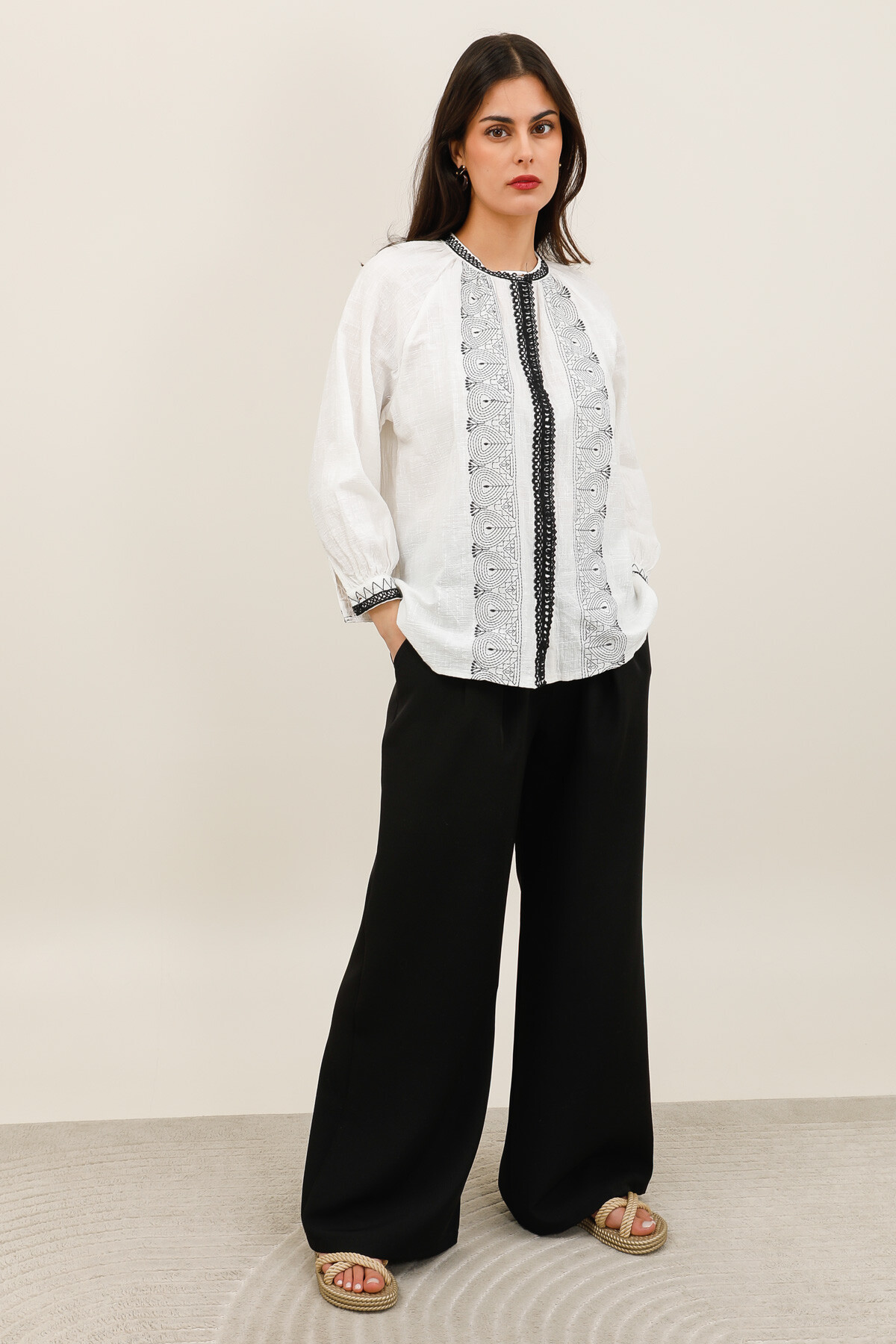 Grossiste Inspiration Studio - Blouse écrue à broderies noires avec manches 3/4, élégante et facile à porter.