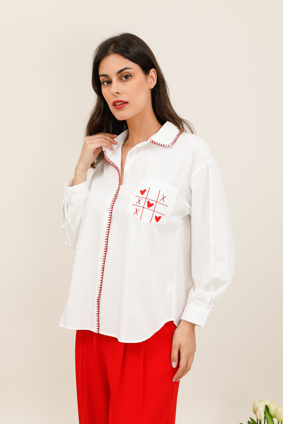 Mayorista Inspiration Studio - Camisa larga lisa con un aire casual y chic, realzada por acabados contrastantes y un bolsillo en el pecho bordado con pequeños corazones gráficos.