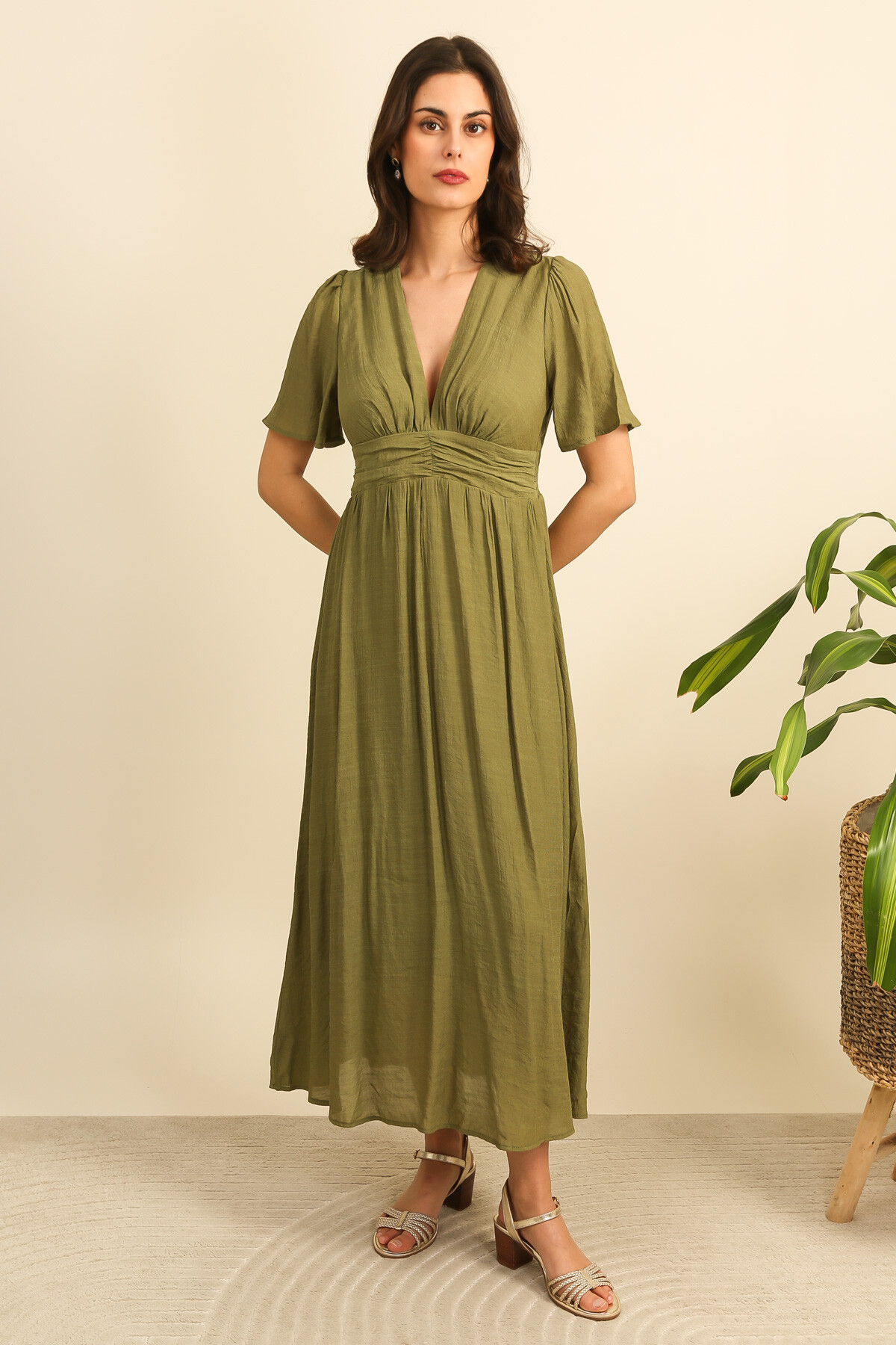 Grossiste Inspiration Studio - Robe longue fluide à décolleté en V, manches courtes légères et tombé aérien, déclinée en plusieurs coloris lumineux.