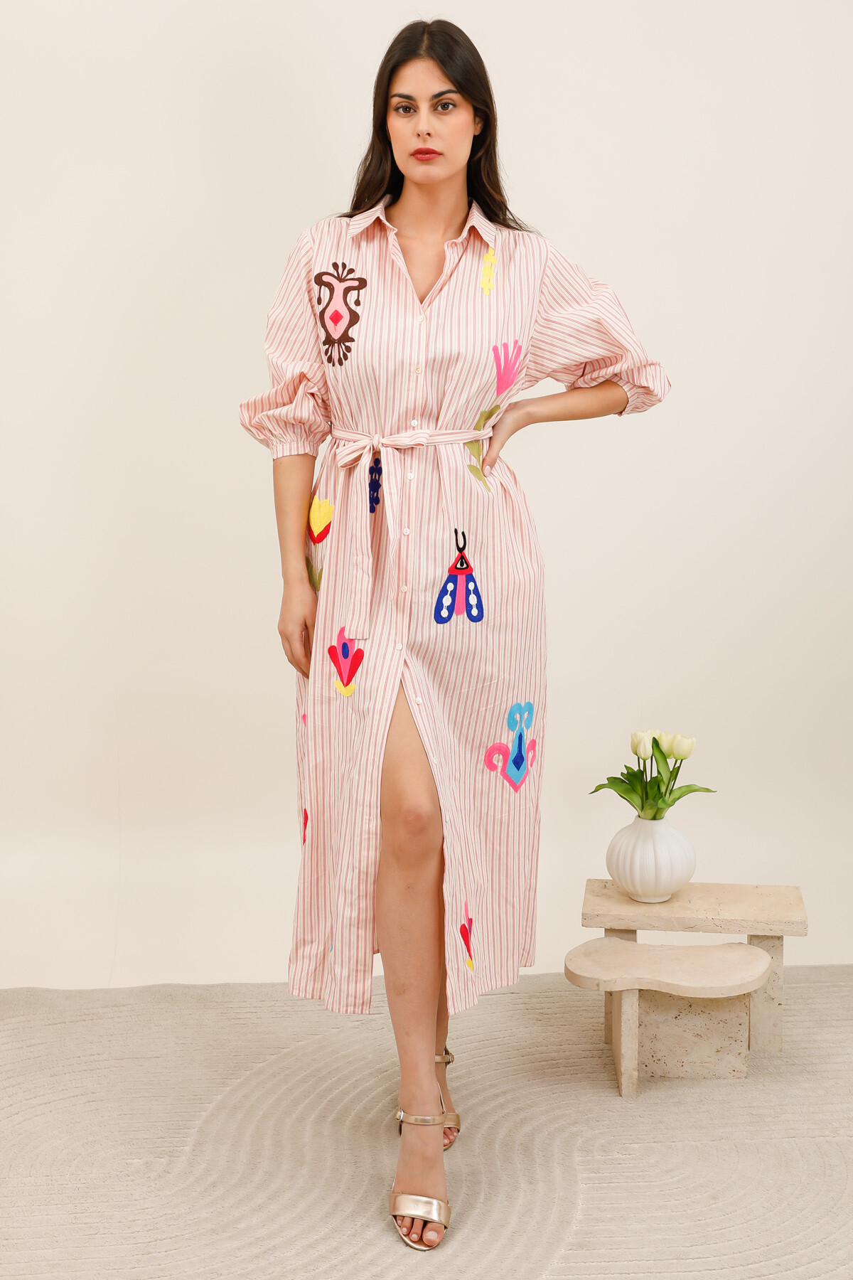 Grossiste Inspiration Studio - Robe chemise longue à rayures, animée par des broderies multicolores au style fantaisie, avec ceinture à nouer pour souligner la taille.