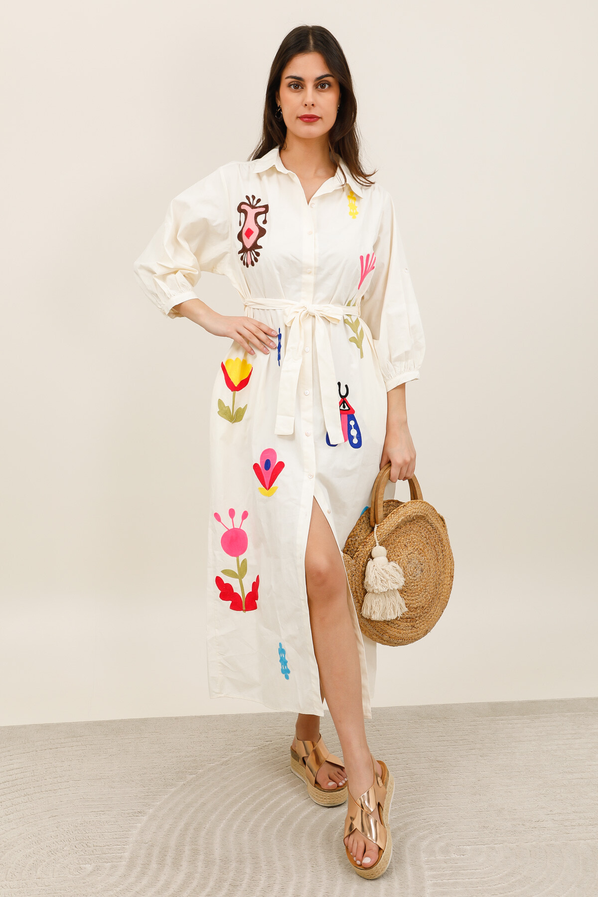 Mayorista Inspiration Studio - Vestido camisero largo color crudo con bordados florales coloridos, con cinturón para atar y mangas 3/4. Elegante y perfecto para el verano.