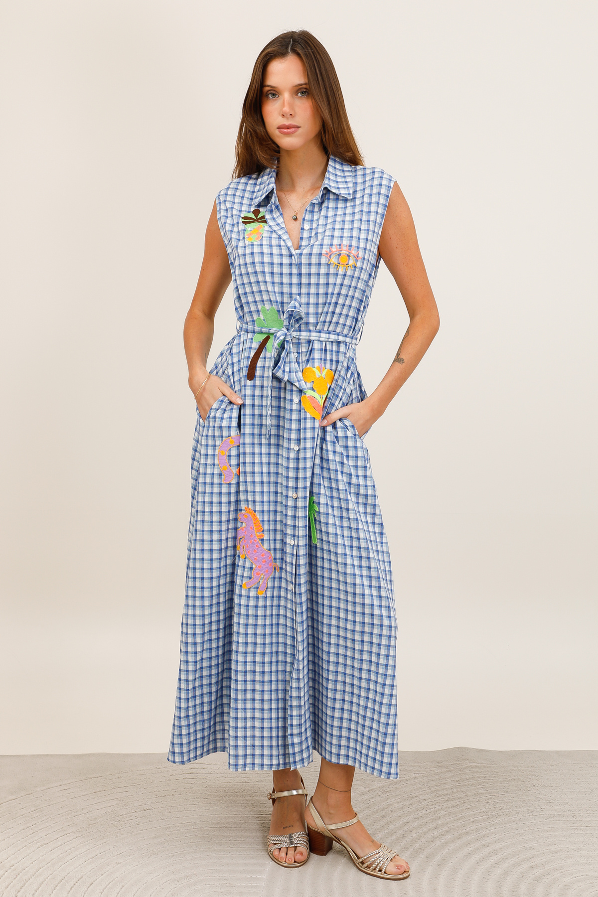 Grossiste Inspiration Studio - Robe chemise longue sans manches à carreaux vichy bleu/blanc, avec broderies fantaisie, ceinture à nouer et poches côtés.