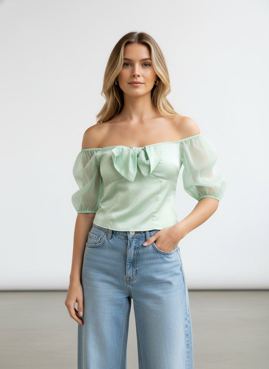 Großhändler J&H Fashion - Elegantes Oberteil mit schulterfreiem Bardot-Ausschnitt, verziert mit einer großen zentralen Schleife und Puffärmeln aus transparentem Voile.
