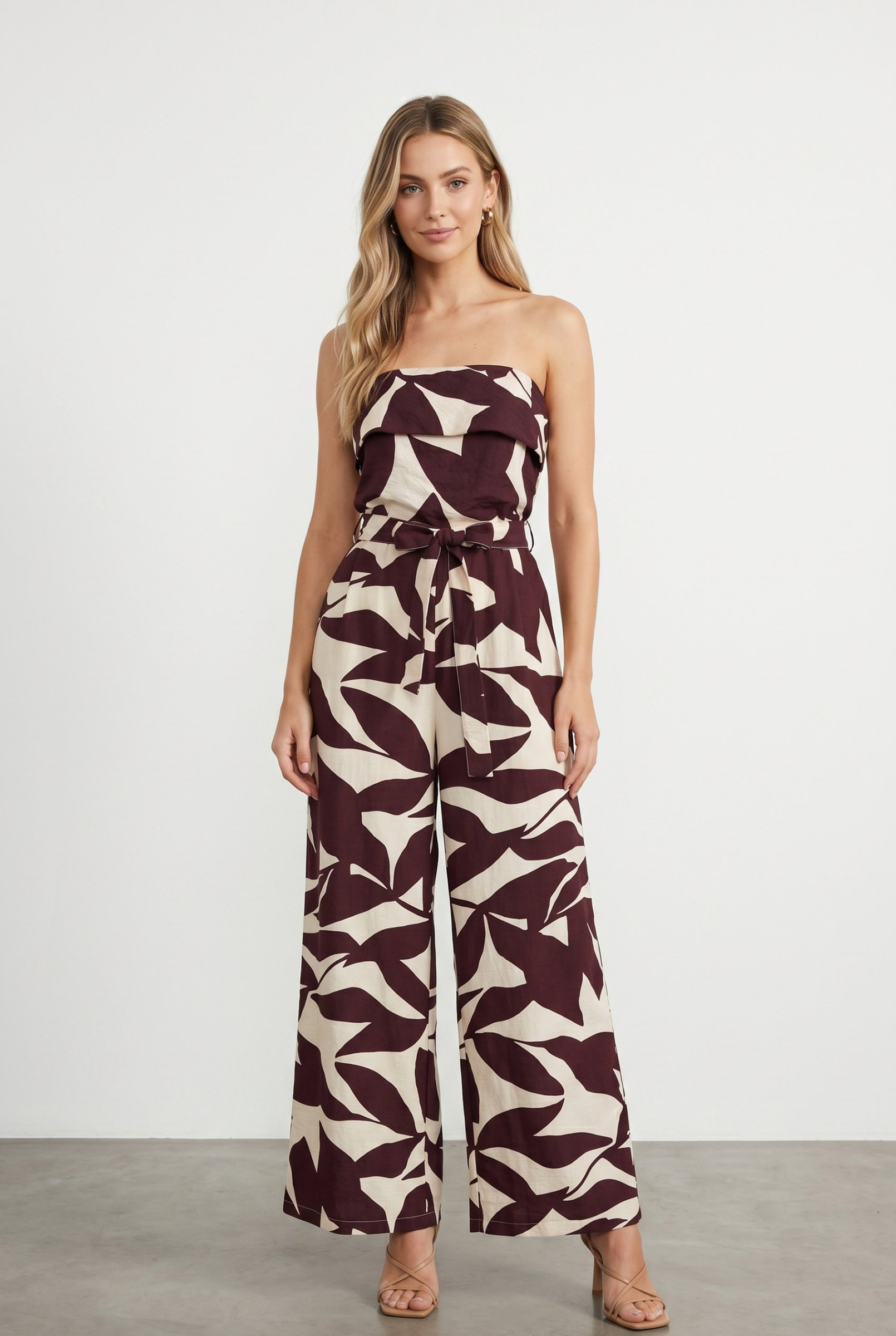 Großhändler J&H Fashion - Schulterfreier Jumpsuit mit abstraktem Blätterdruck, weitem Bein und Bindegürtel für eine elegante Silhouette.