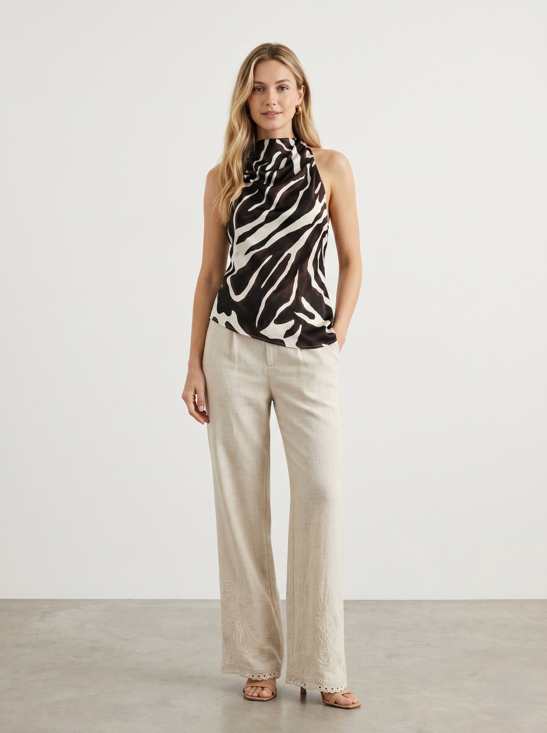 Großhändler J&H Fashion - Elegantes Set bestehend aus einem fließenden Zebra-Print-Haltertop und einer weiten beigen Leinenhose mit zarten Stickereidetails.