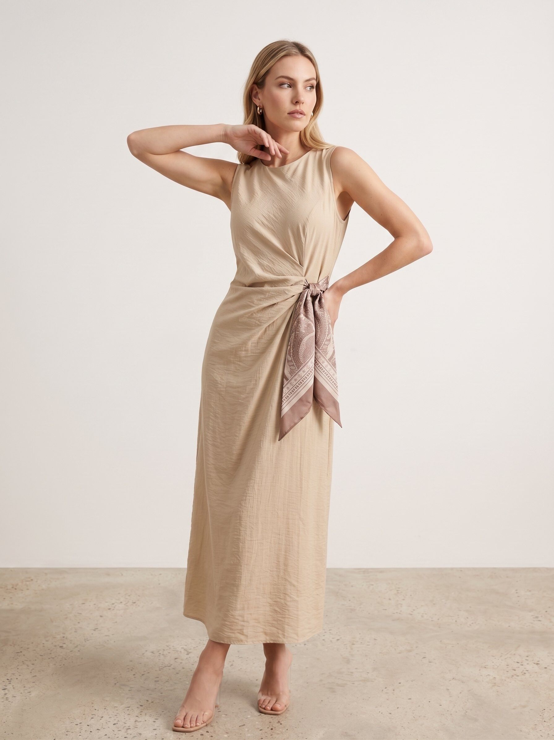 Grossiste J&H Fashion - Robe longue sans manches présente une coupe élégante avec un effet drapé raffiné, soulignée par un nœud latéral à motif satiné.robe longue sans manches