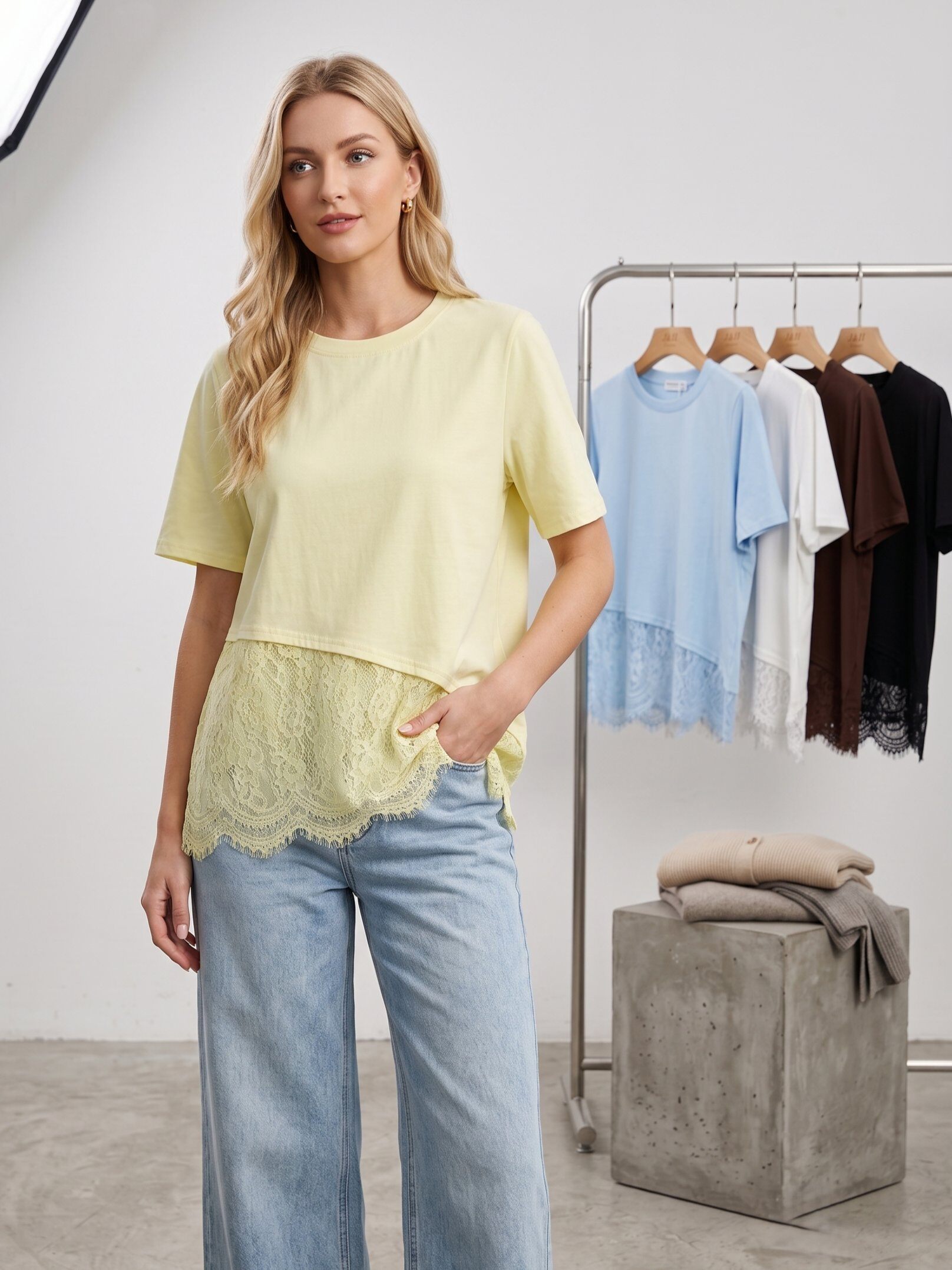 Mayorista J&H Fashion - Camiseta fluida de manga corta y cuello redondo, destacada por un elegante juego de asimetría y delicados acabados de encaje floral en el bajo.