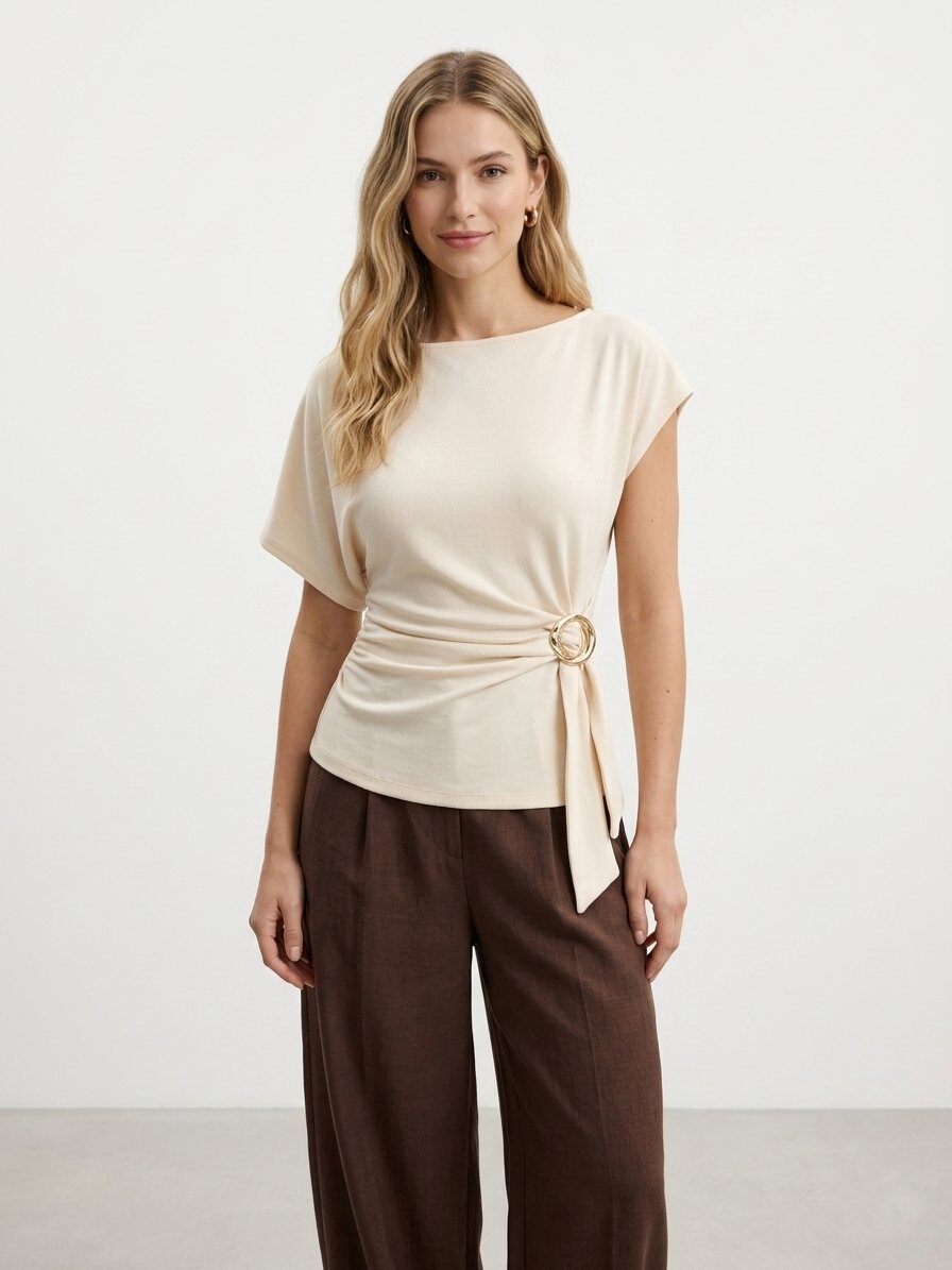 Grossiste J&H Fashion - Haut à manches courtes présente une encolure arrondie et un élégant détail drapé sur le côté, maintenu par un anneau métallique doré.