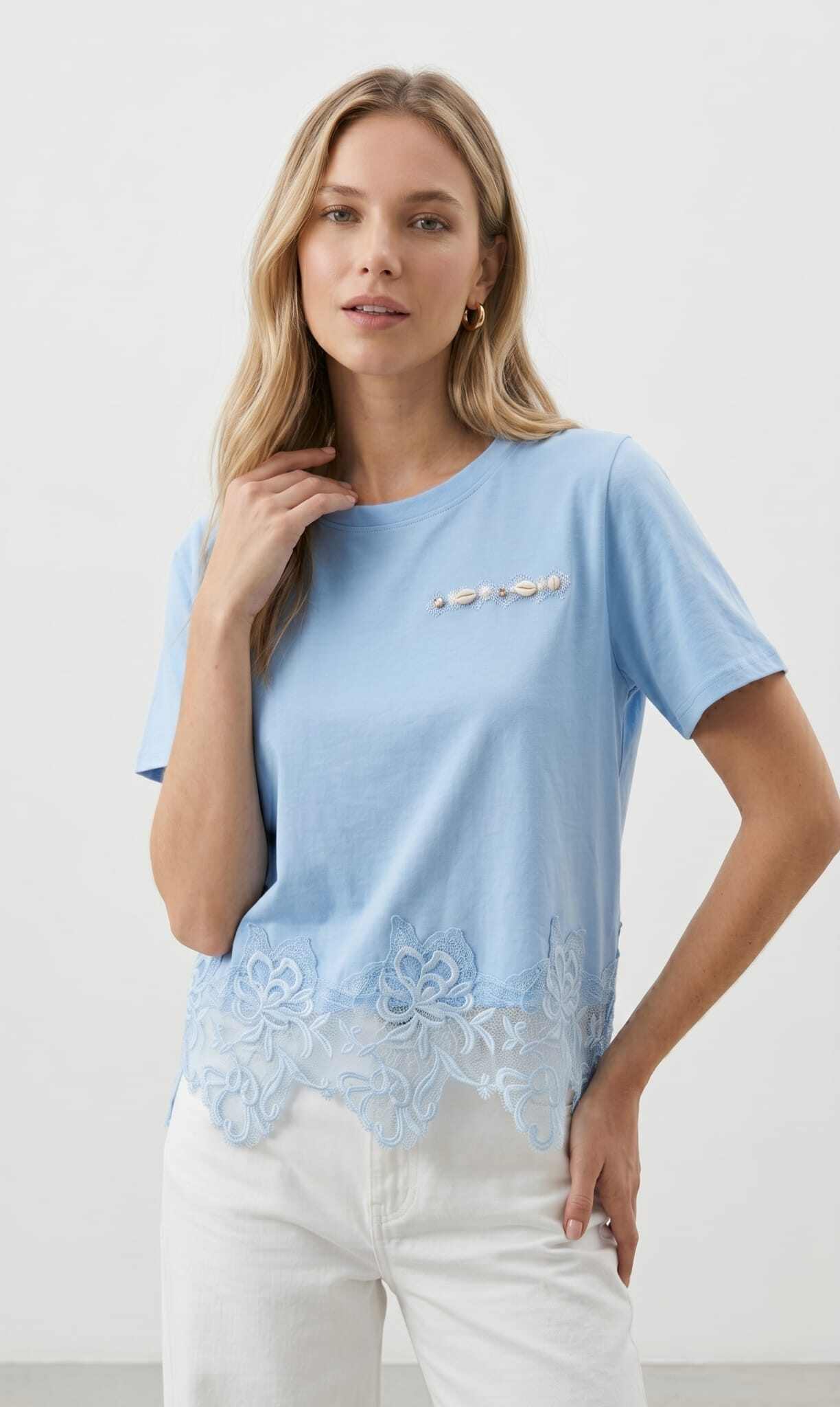 Grossista J&H Fashion - T-shirt a maniche corte con un elegante bordo in pizzo guipure traforato alla base e un delicato dettaglio ornamentale sul petto.