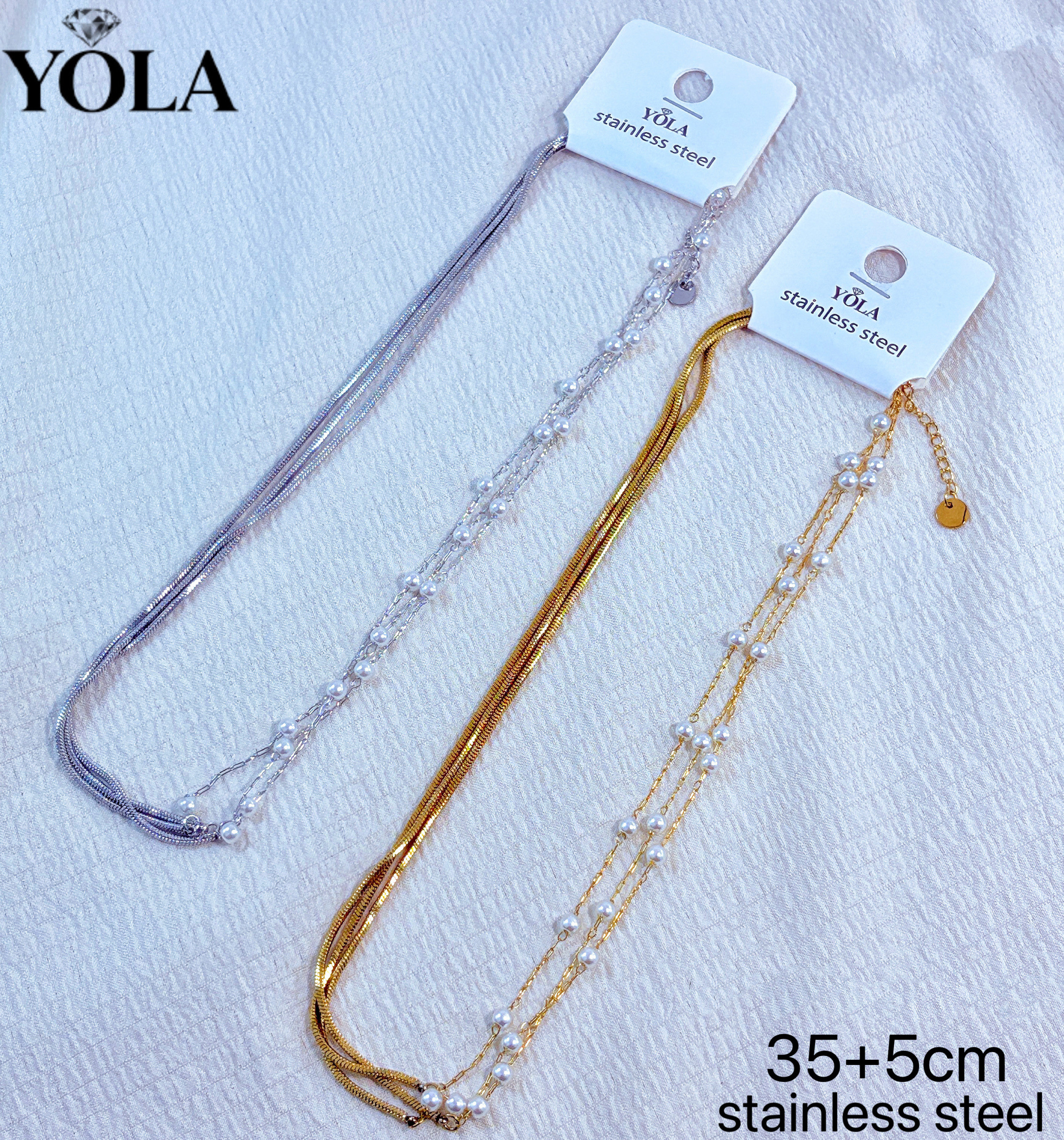 Grossiste JESSICA - Il s'agit d'un collier multi-rangs en perles et chaîne serpent, fabriqué en acier inoxydable, avec une longueur de chaîne de 35 cm + 5 cm de rallonge. Le collier présente un design à trois chaînes, dont une est une chaîne serpent lisse, et les deux autres