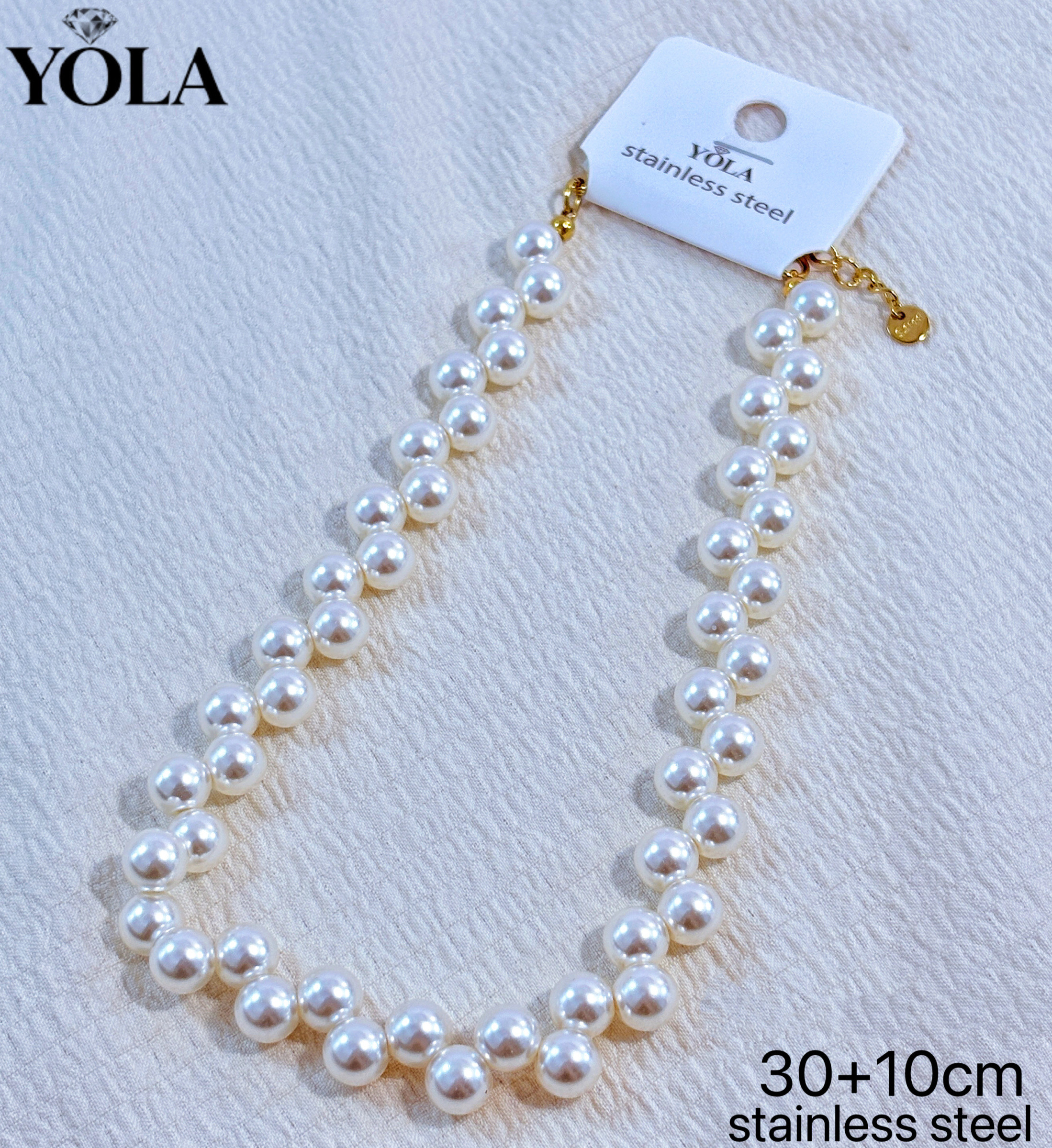 Grossiste JESSICA - Il s'agit d'un collier ras du cou en perles rondes, fabriqué en acier inoxydable, avec une longueur de chaîne de 30 cm + une chaîne d'extension de 10 cm. Le collier est composé de fausses perles pleines et rondes, assorties à un fermoir en métal doré et u