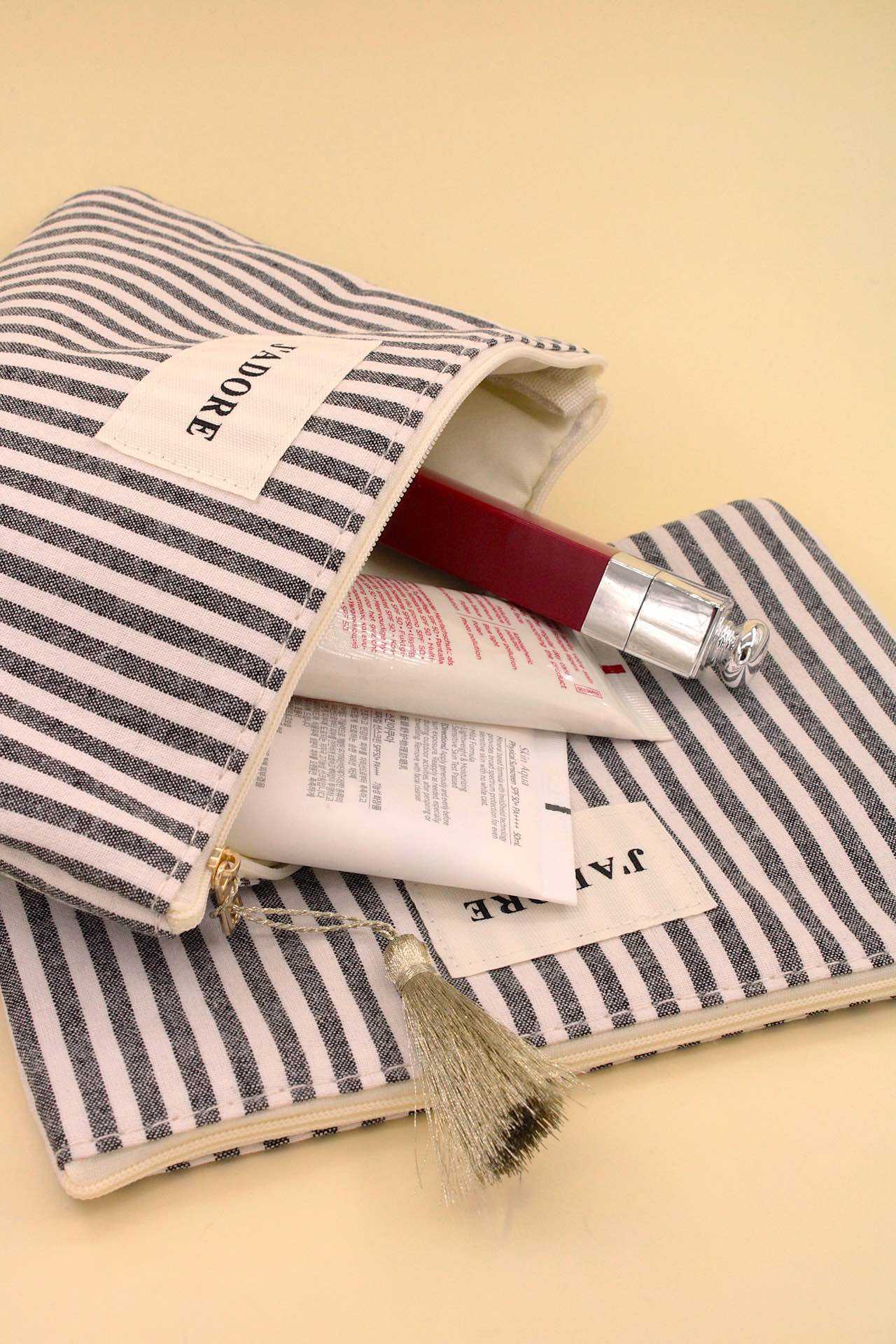 Grossiste MAISON OKAMI - Pochette rayée en tissu avec fermeture éclair et pompon