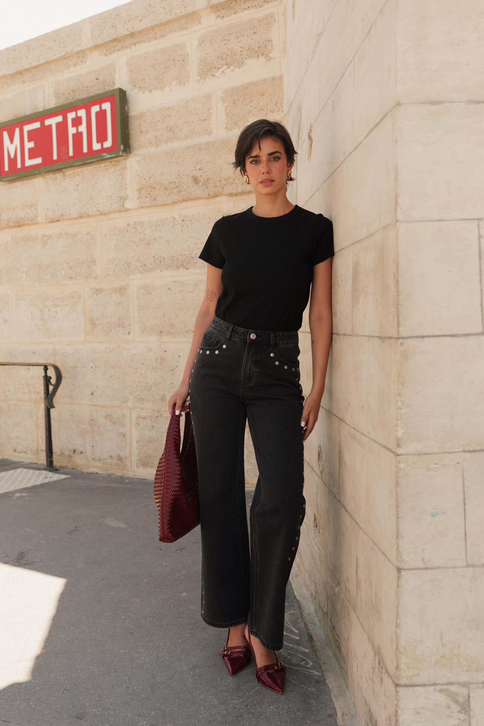 Jean droit taille haute en denim noir délavé, orné de rivets sur les côtés. Longueur idéale pour être porté avec des sneakers, pour un look tendance et décontracté.