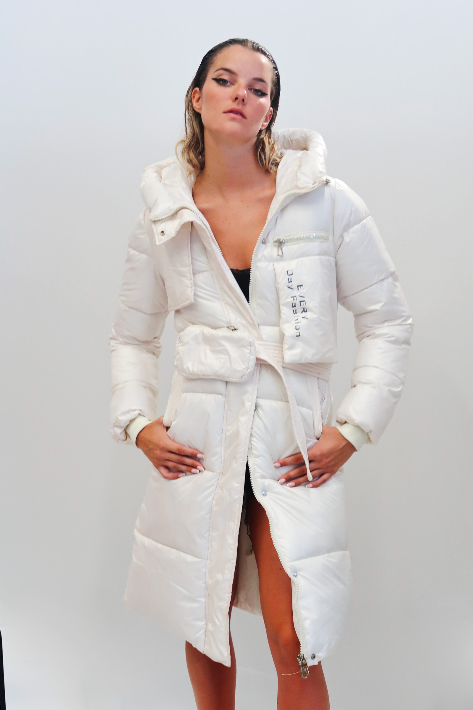 Grossiste QUEEN DRAMA - Manteau long pour femme avec fermeture frontale à zip et bouton, agrémenté d'une ceinture avec porte-monnaie intégré et poches asymétriques au design original