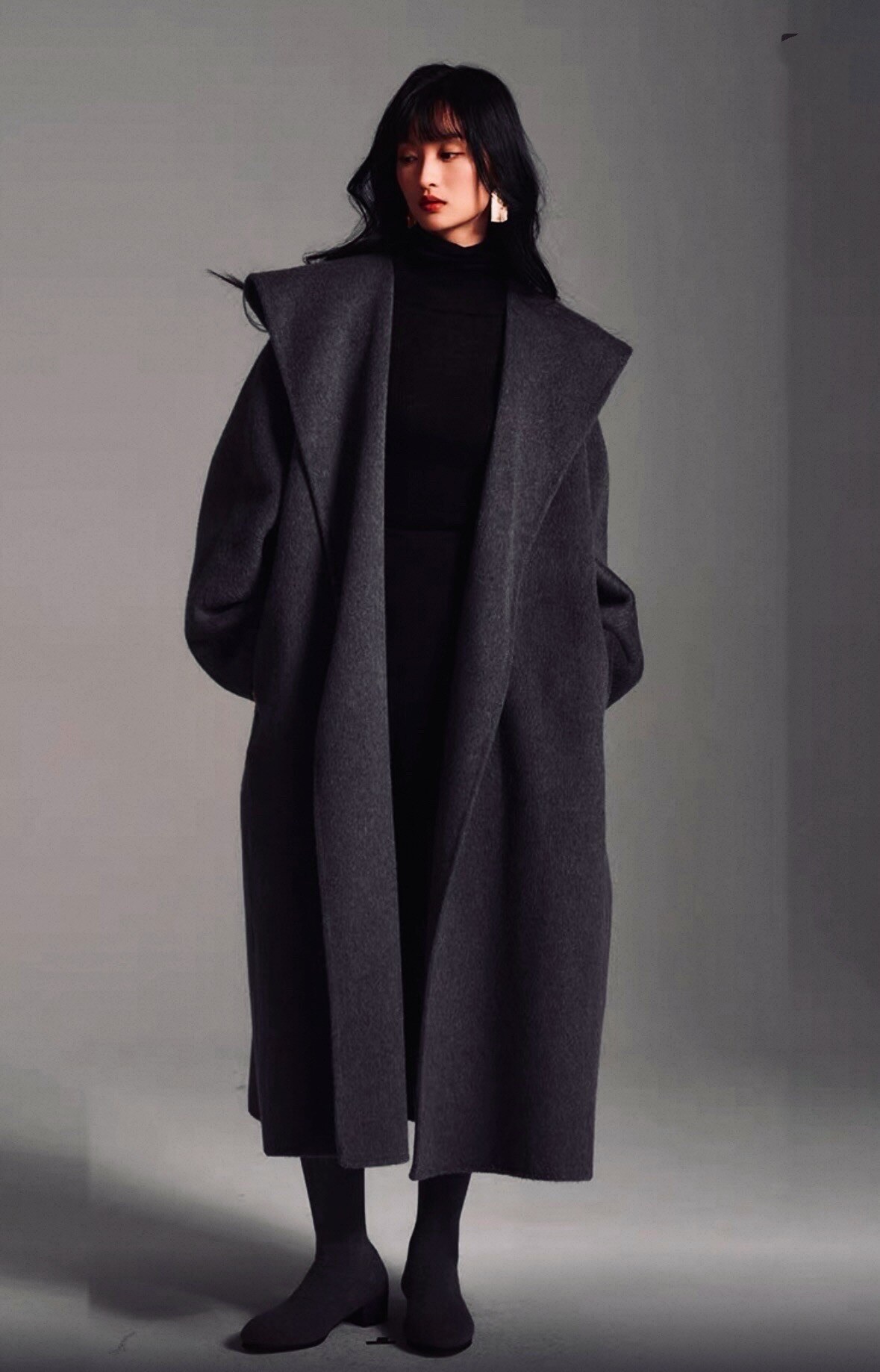 Ce manteau long ceinturé incarne l’élégance intemporelle. Confectionné dans une laine douce et structurée, il enveloppe la silhouette avec justesse tout en offrant chaleur et confort. Son col large et sa coupe oversize ajoutent une touche moderne et raffinée, parfaite pour affronter la saison froide avec style.
