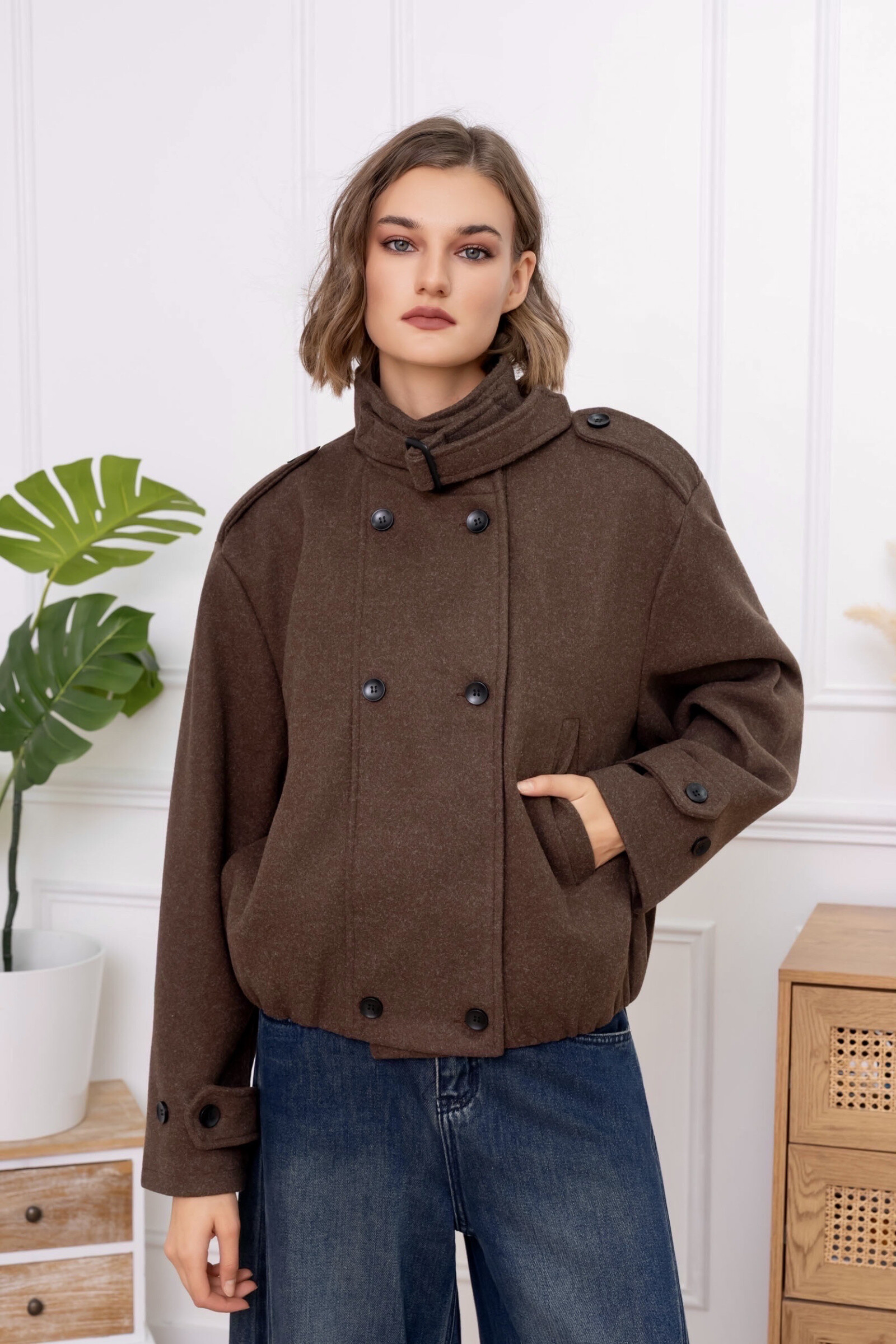 Un manteau court noir à double boutonnage, col montant avec boucle et épaules boutonnées. Sa coupe ample et élégante allie confort et sophistication pour un style intemporel. ?