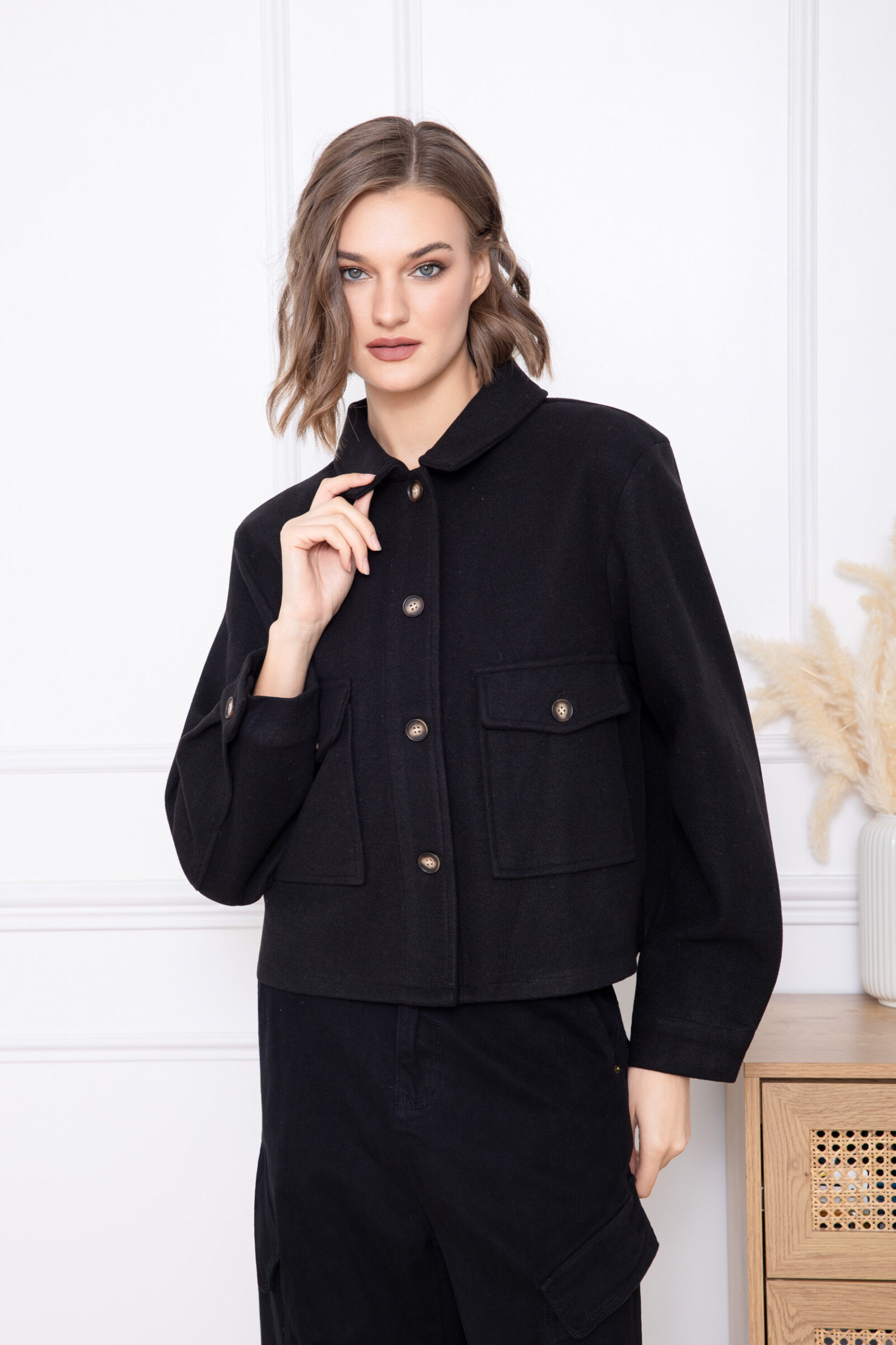 This short jacket is distinguished by its straight and structured cut, offering an elegant and contemporary look. Made from a soft and slightly textured material, it ensures optimal comfort while maintaining a clean drape. The classic collar adds a timeless touch, while the buttoned front closure reinforces its refined style. The patch pockets add a practical and aesthetic dimension, and the long sleeves slightly tightened at the wrists guarantee a harmonious fit. A versatile piece, ideal for putting together neat everyday or professional outfits.