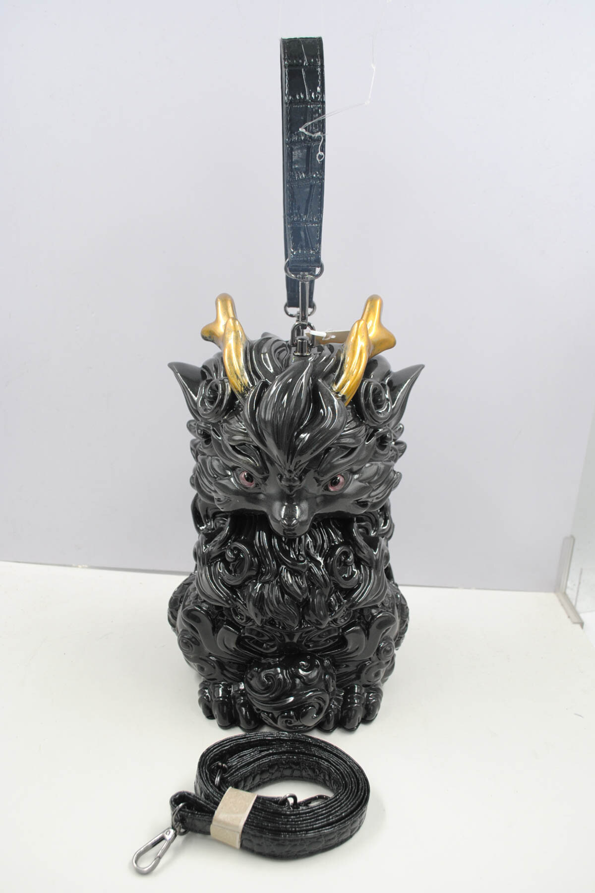Wholesaler SyStyle - Qilin Handbag. Inspired by the mythical qilin, it blends art and modernity. Shiny black resin, dynamic textures, shimmering golden horns.